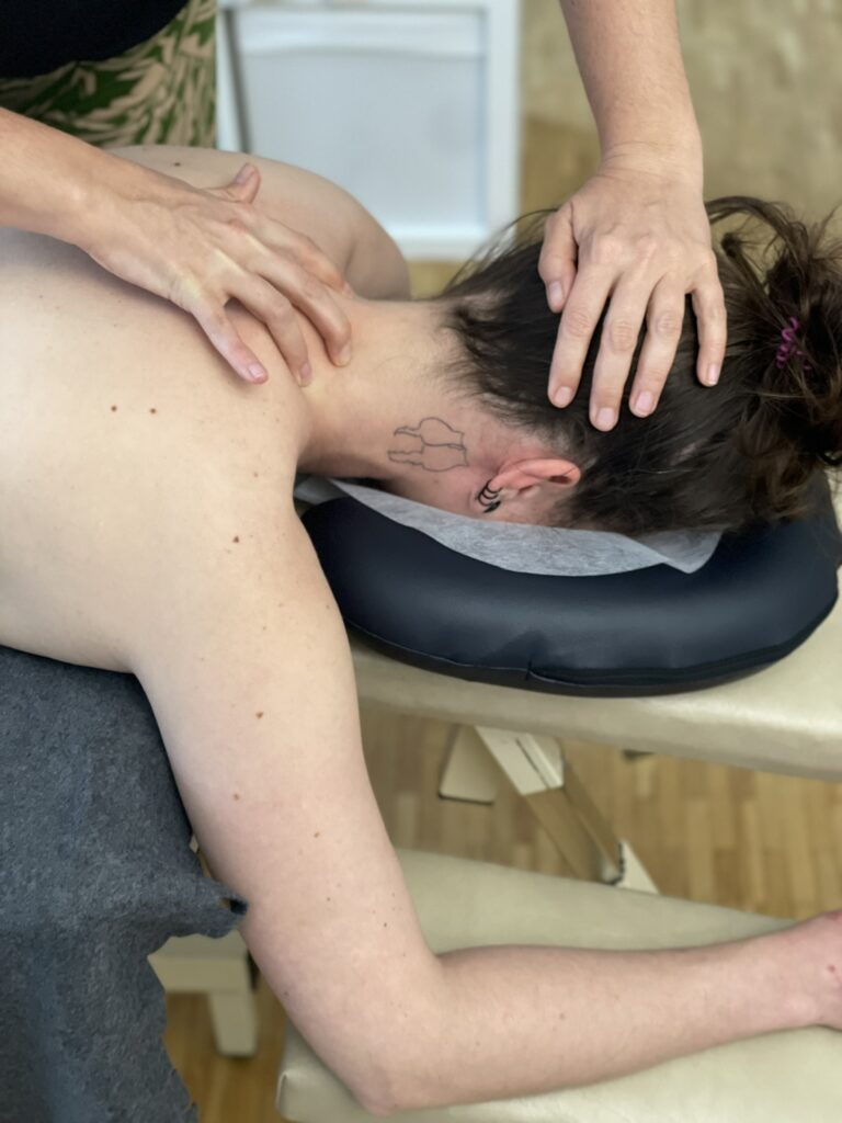 Eine entspannende Nackenmassage wird auf einer bequemen Massageliege durchgeführt. Der Fokus liegt auf den Händen des Therapeuten, die gezielte Druckpunkte und Techniken anwenden, um Spannung und Stress in der Nackenmuskulatur des Klienten zu lösen. Ideal für Wellness und Stressabbau.